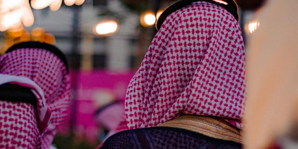 A group of men in traditional Saudi dress enjoying an outdoor gathering, showcasing cultural attire.