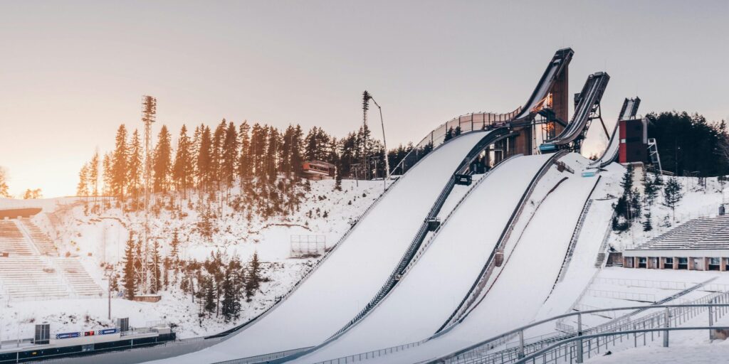 Snow-covered ski jumps in Lahti during winter golden hour with a serene and frosty landscape.