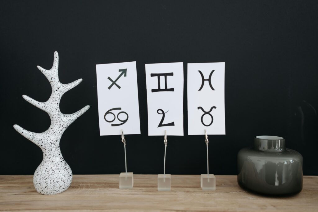 Minimalist decor showcasing zodiac signs with modern elements on a wooden table.